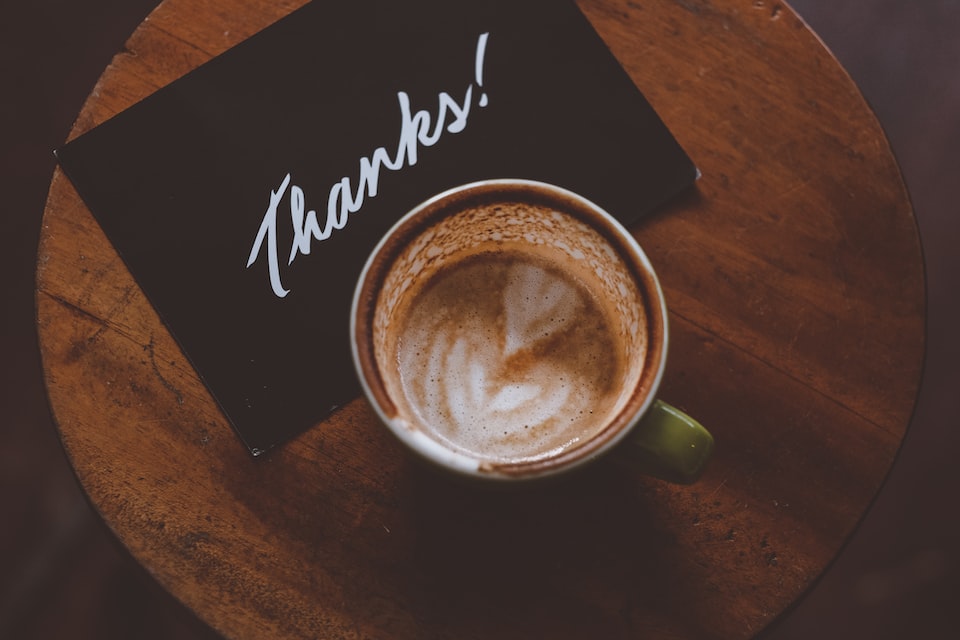A coffee with a note aside saying thanks.